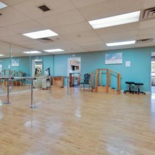 An empty dance studio with mirrors and a ballet barre along the wall.