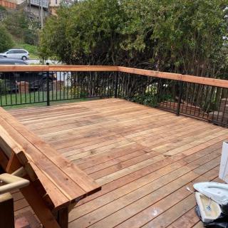 A newly constructed wooden deck with railing in a backyard setting.