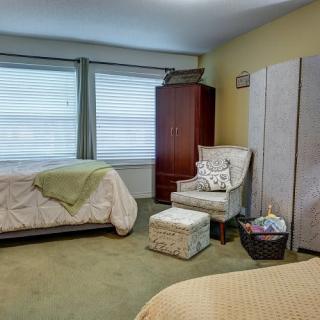 A cozy bedroom with two beds, a chair, and a cabinet near the window.