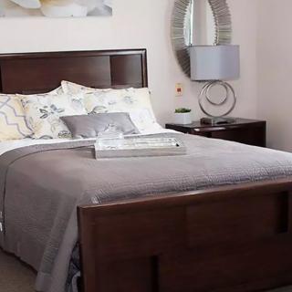 A cozy bedroom with a neatly made bed, nightstand, and stylish decor.