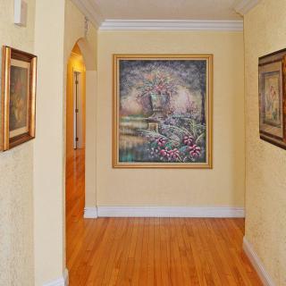 A hallway with framed paintings on the walls and a polished wooden floor.