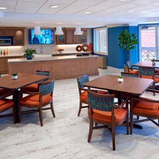 A modern dining area with wooden tables and chairs, featuring contemporary decor and lighting.