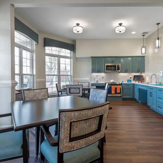 A modern kitchen and dining area with hardwood floors, large windows, and stylish lighting.