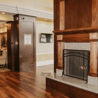 A cozy living room with a classic wooden fireplace and polished wooden flooring.
