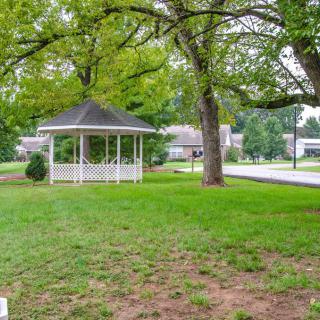 A peaceful park scene featuring a gazebo surrounded by lush greenery and trees.