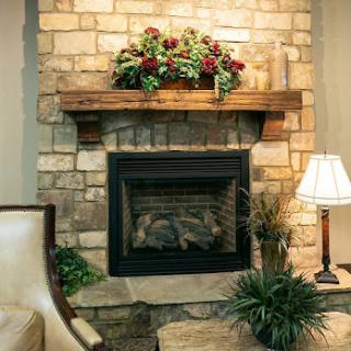 Cozy living room featuring a stone fireplace adorned with floral arrangements.