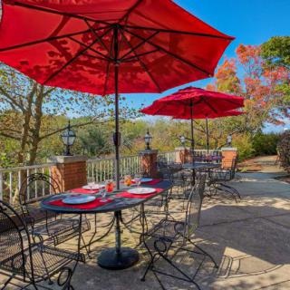 A scenic outdoor patio with dining tables and red umbrellas on a sunny day.