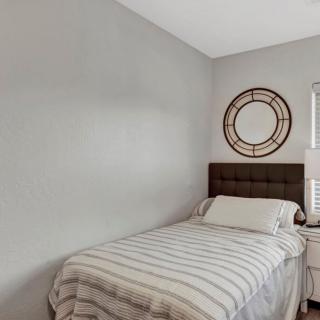 A cozy bedroom with a single bed featuring striped bedding and minimalistic decor.