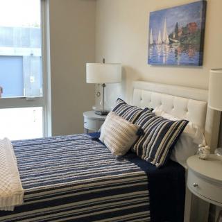 A modern bedroom featuring striped bedding, twin lamps, and artwork above the bed.