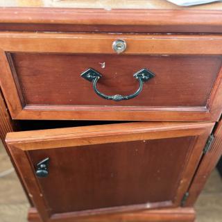 A vintage wooden cabinet with a drawer and door, featuring metal handles.