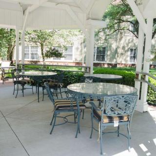A cozy outdoor gazebo with tables and chairs surrounded by lush greenery.