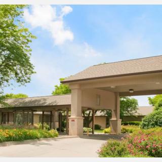 A well-maintained building entrance surrounded by lush greenery under a clear blue sky.