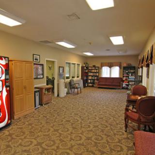 A spacious waiting room with a vending machine, comfortable seating, and warm lighting.