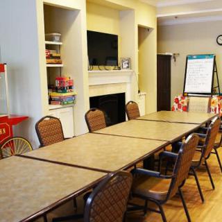 A meeting room with a long table, several chairs, a TV, and a popcorn machine.