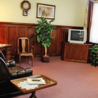 A vintage-style living room featuring wood paneling, a small television, and traditional furnishings.