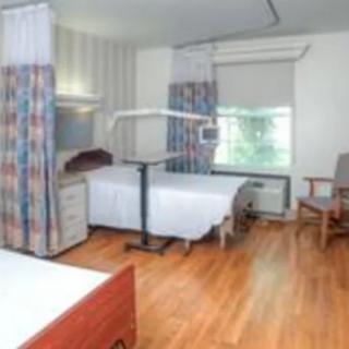 A clean and well-lit hospital room featuring beds, curtains, and comfortable seating.