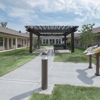 A well-maintained courtyard featuring a pergola, surrounded by buildings and greenery.
