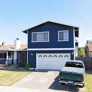 A two-story blue house with a garage and a green truck parked in the driveway.