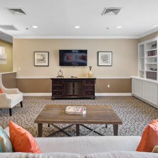 A cozy living room with a TV mounted on the wall, surrounded by comfortable seating and tasteful decor.