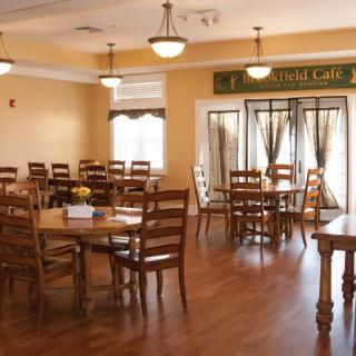 A cozy dining room with wooden tables and chairs, well-lit by overhead lamps.