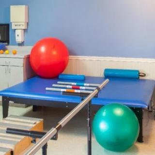 A therapy room equipped with exercise balls and parallel bars for rehabilitation exercises.