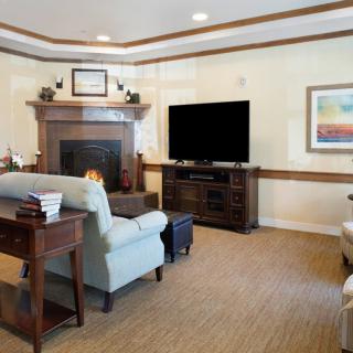 A cozy living room featuring a sofa, large television, and fireplace.