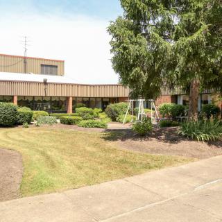 A view of a modern building surrounded by well-maintained greenery and a sidewalk.