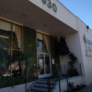 An exterior view of a building with greenery and a visible address sign.