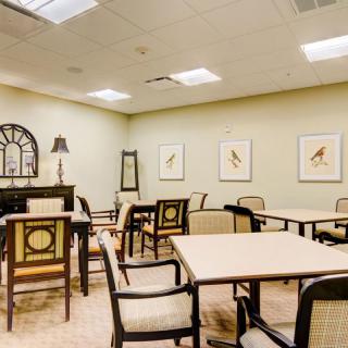An elegantly furnished dining area with tables and chairs, decorated with wall art and ambient lighting.