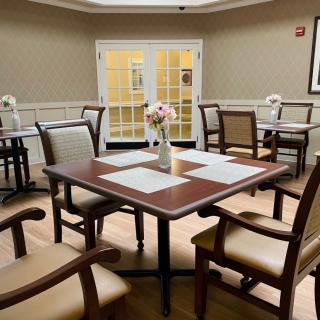 A cozy dining area with neatly arranged tables and chairs, featuring a vase of flowers as a centerpiece.