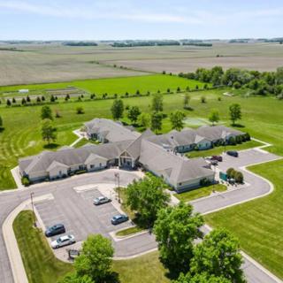 Aerial view of a building complex surrounded by greenery and fields in the countryside.
