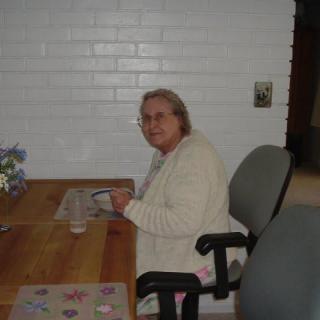 An elderly person sitting at a dining table indoors.