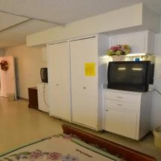 A living room with a television on a cabinet, surrounded by white furniture and decor.
