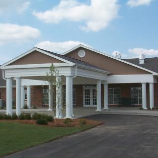 A building with a prominent entrance featuring columns under a partly cloudy sky.