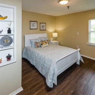 A cozy bedroom with a neatly made bed, decorated with pillows and artwork on the walls.