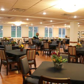 An empty dining area with neatly arranged tables and chairs, well-lit interior, and decorative plants.