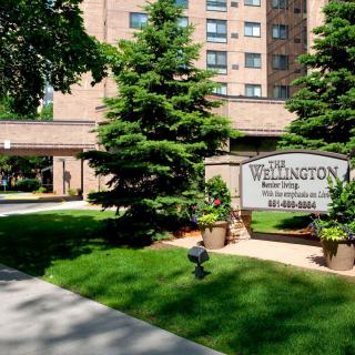 Entrance of The Wellington apartment building with well-maintained landscaping.