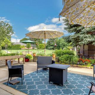 A sunny outdoor patio with furniture, umbrella, and a lush garden backdrop.