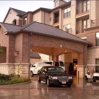 Hotel entrance with parked vehicles and a covered driveway.