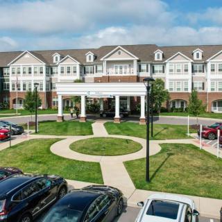 A modern residential building with a parking lot and landscaped entrance.