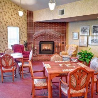 A cozy living room with a fireplace, featuring a table and chairs set against a brick wall.