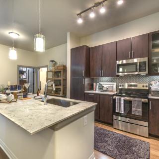A modern kitchen interior featuring dark cabinets and stainless steel appliances.