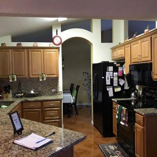 A cozy kitchen with wooden cabinets, a black refrigerator, and a granite countertop.