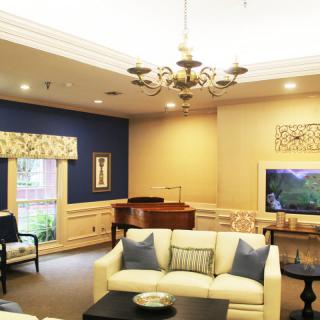 A cozy living room with a piano, elegant chandelier, and blue accent wall.
