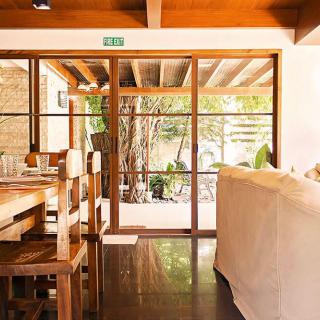 A cozy restaurant interior with wooden furniture and glass doors opening to a garden view.