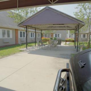 A residential area featuring a central gazebo with outdoor furniture and surrounding houses.