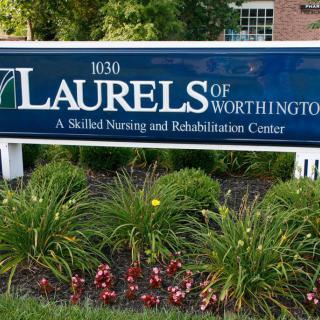 A sign for Lauralsof Worthington, a skilled nursing and rehabilitation center, surrounded by a garden.