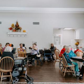 A group of elderly individuals gathered in a nursing home common area, socializing and spending time together.