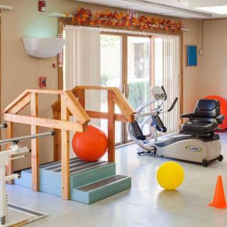 An indoor physical therapy room equipped with exercise machines and therapy tools.