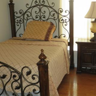 A cozy bedroom with an antique wrought iron bed frame and a matching lamp on a wooden floor.